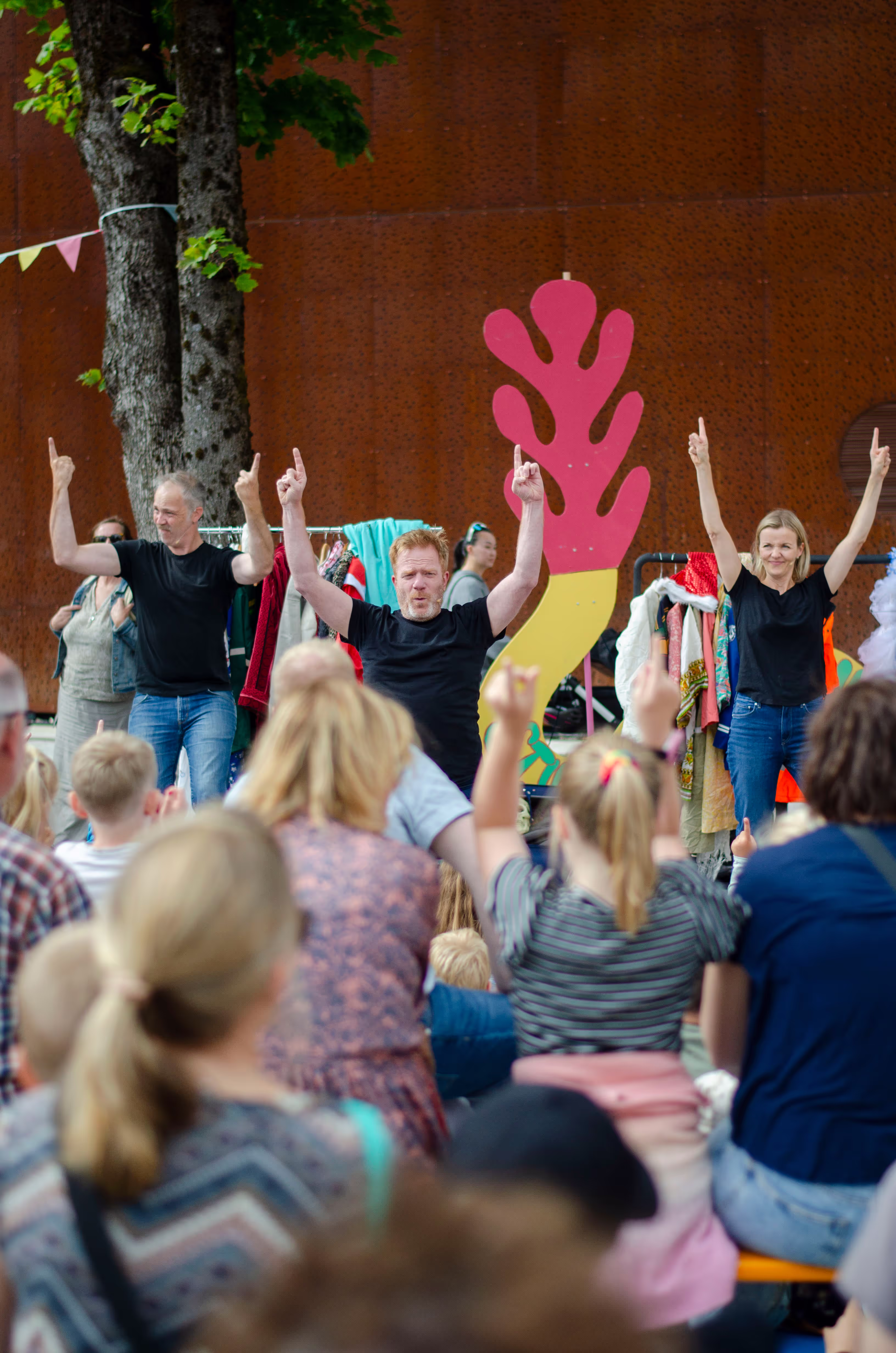 Et bilde fra forestillingen Plutselig Barneteater hvor tre skuespillere underholder et stort publikum.
