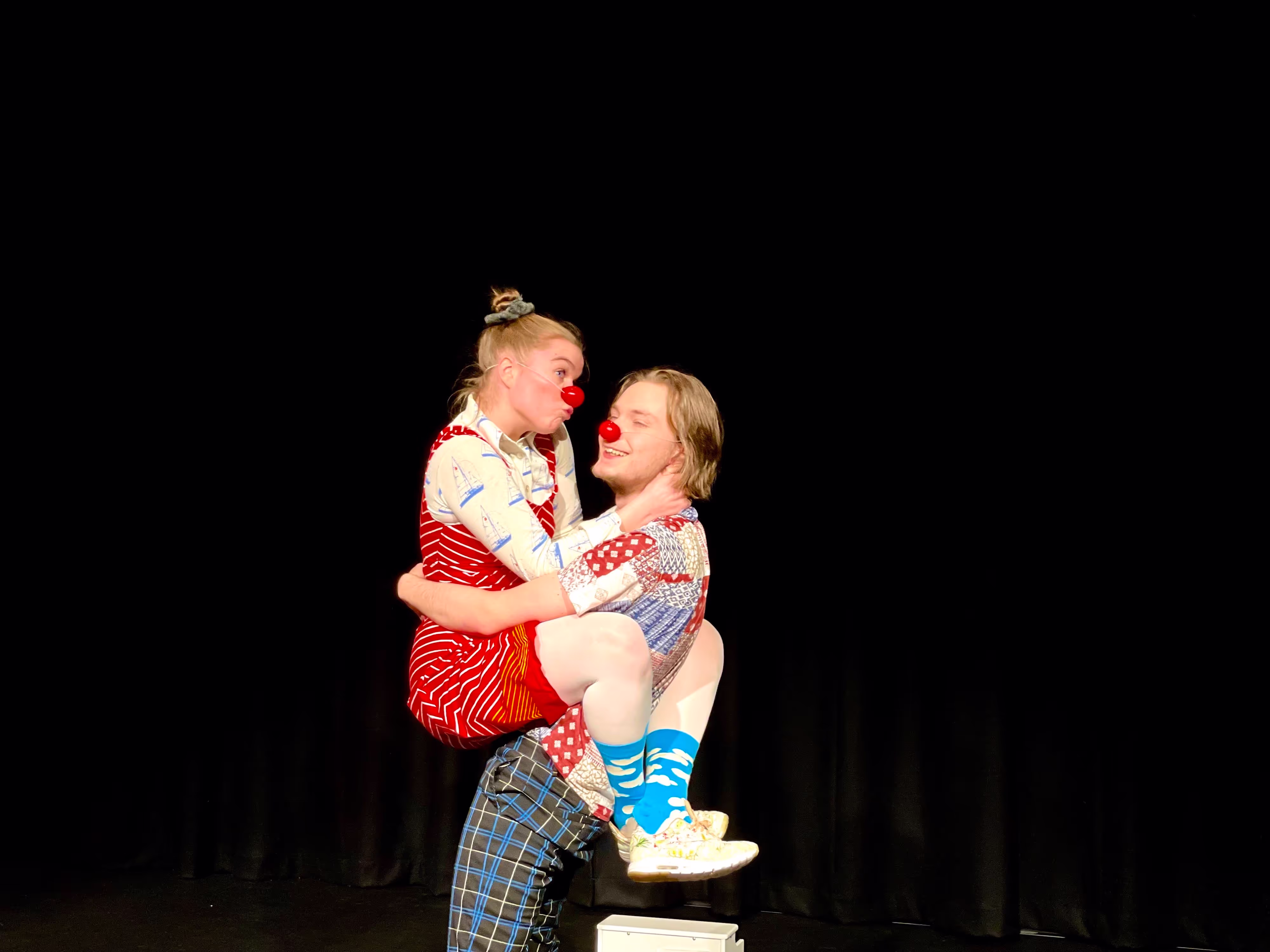 Et bilde fra forestillingen Verdens Beste Historie. To klovner omfavner hverandre på en latterlig måte.