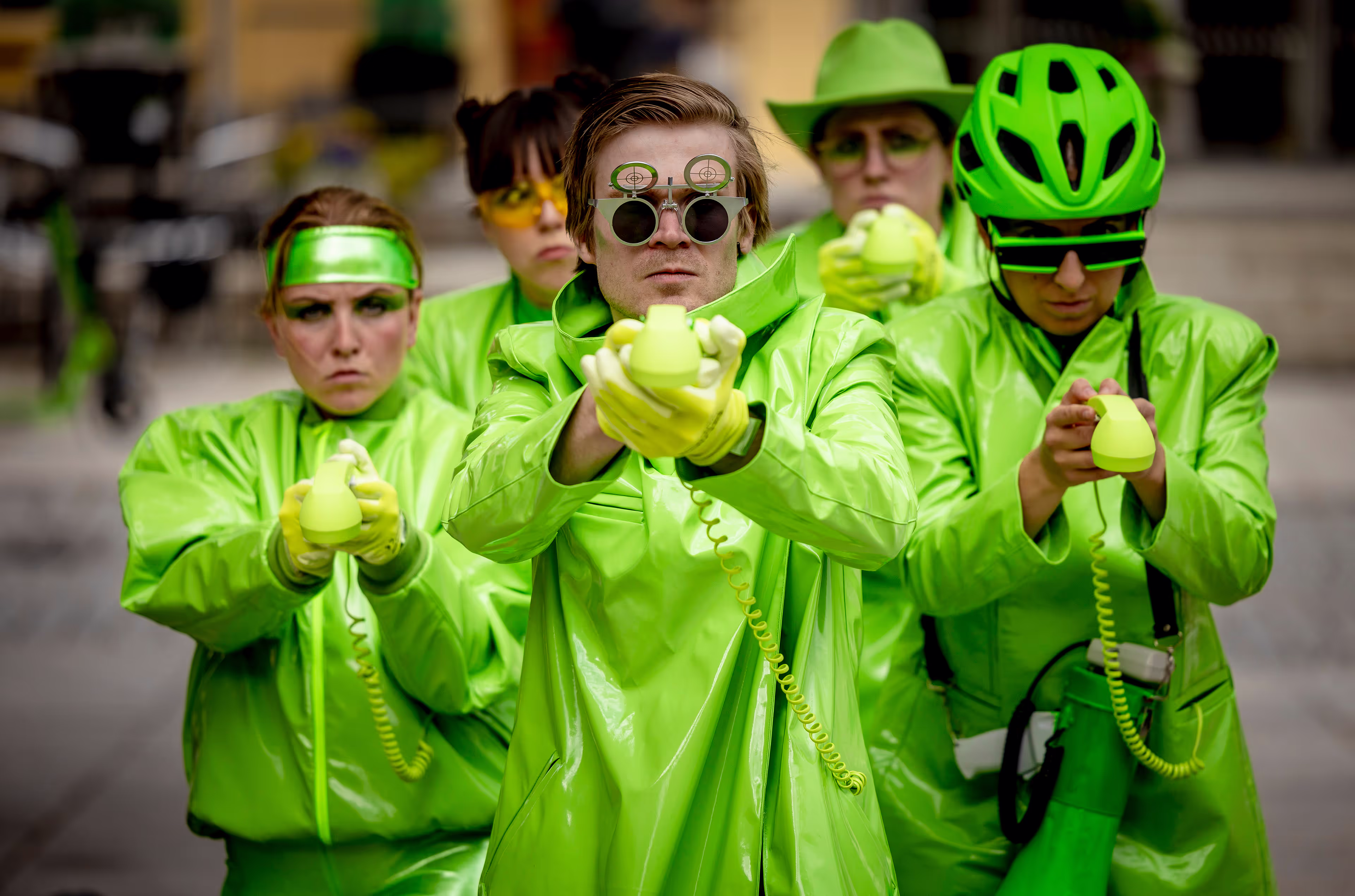 Et bilde fra forestillingen Agentene og det sjukt farlige oppdraget. Vi ser fem grønnkledde mennesker som peker med objekter mot kamera.