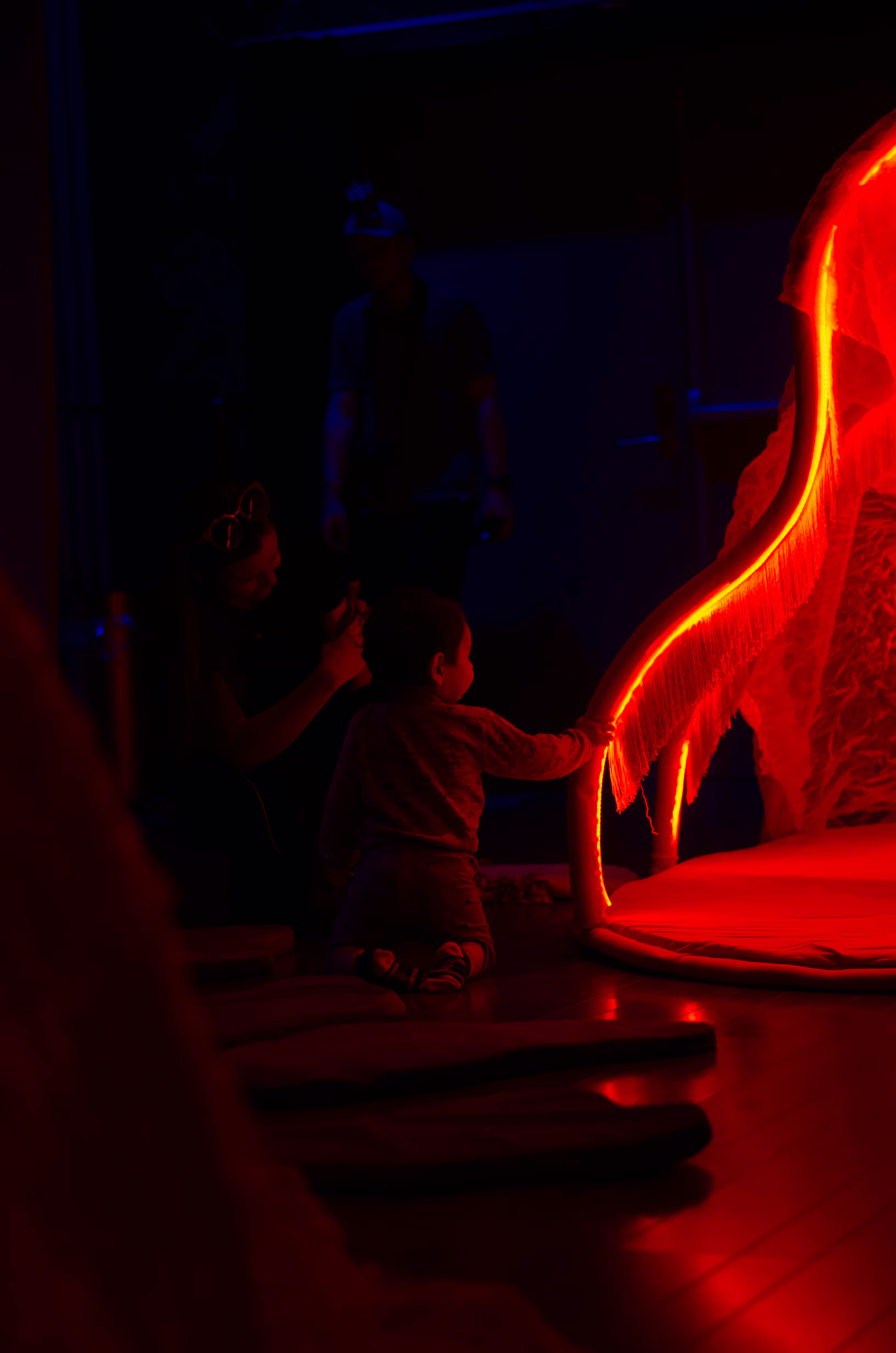 Noen barn sitter i et mørkt rom og undersøker et lysende rødt objekt.