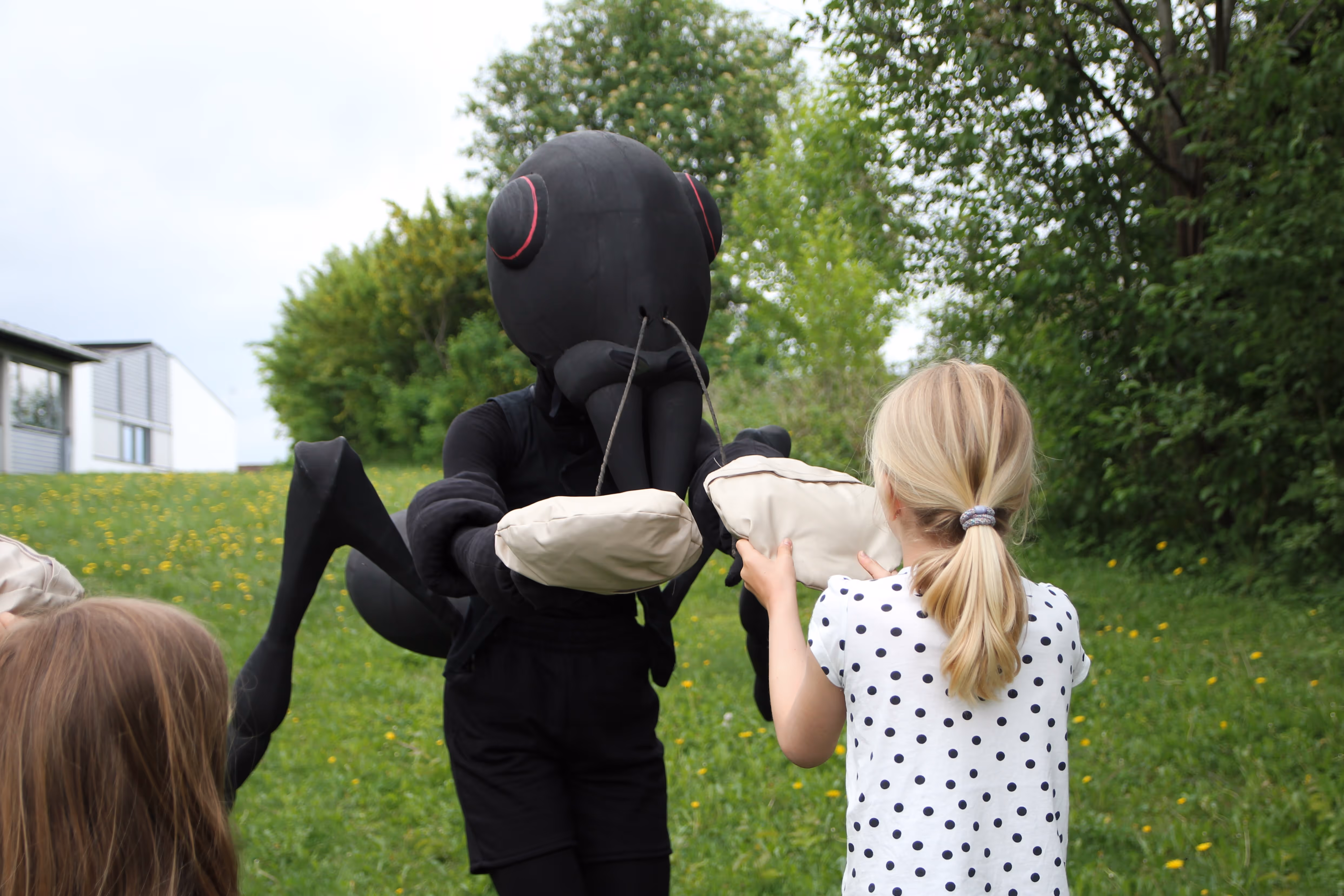 Vi ser en stor maur foran noen trær som strekker hendene ut mot et barn
