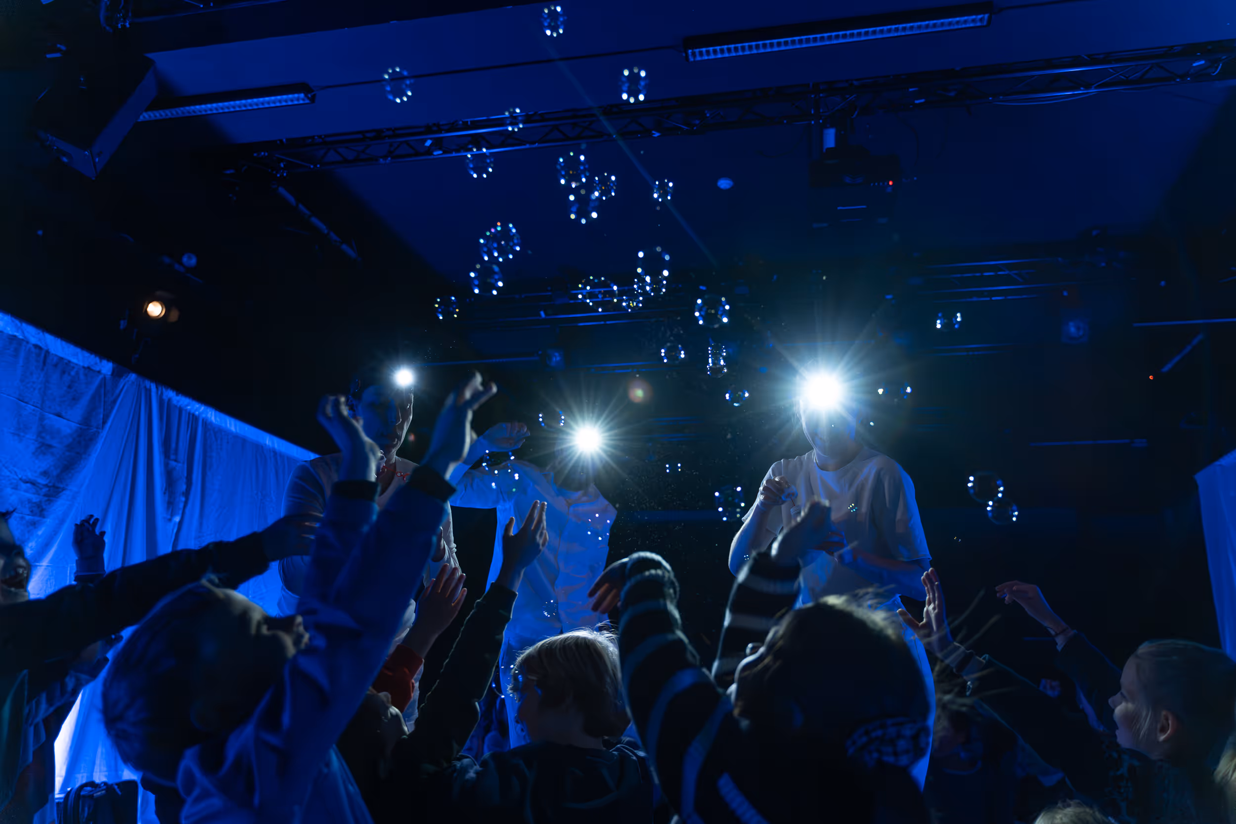 Såpebobler over barn som er lyst opp av lommelykter. Bakgrunnen er blå.