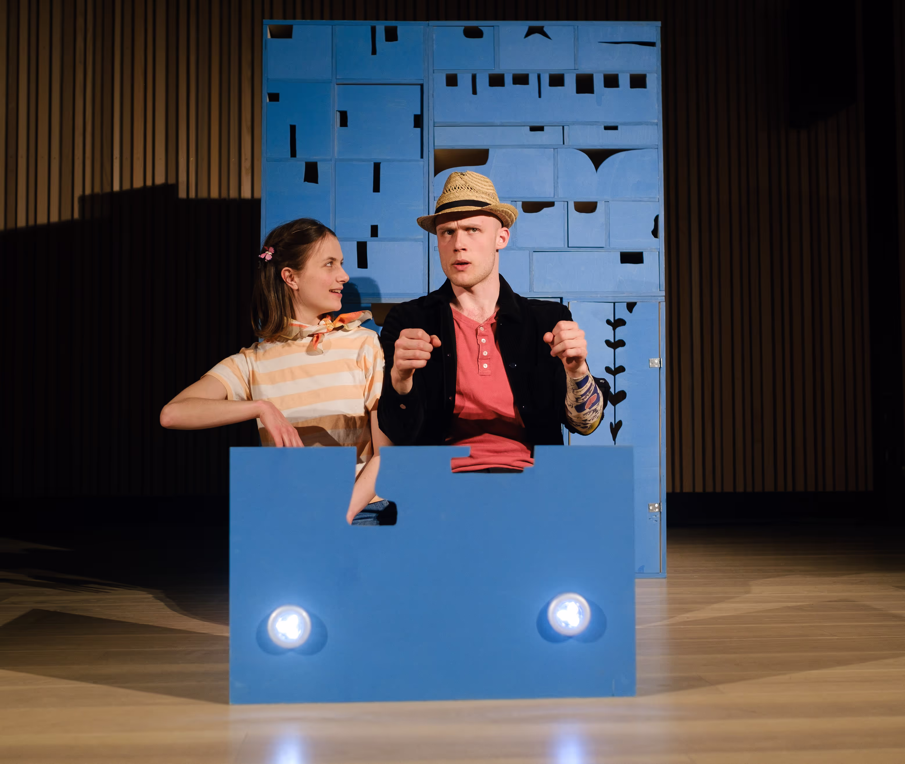 Et bilde fra forestillingen Verden har ingen hjørner. To mennesker sitter i en blå skuff foran en blå kommode.